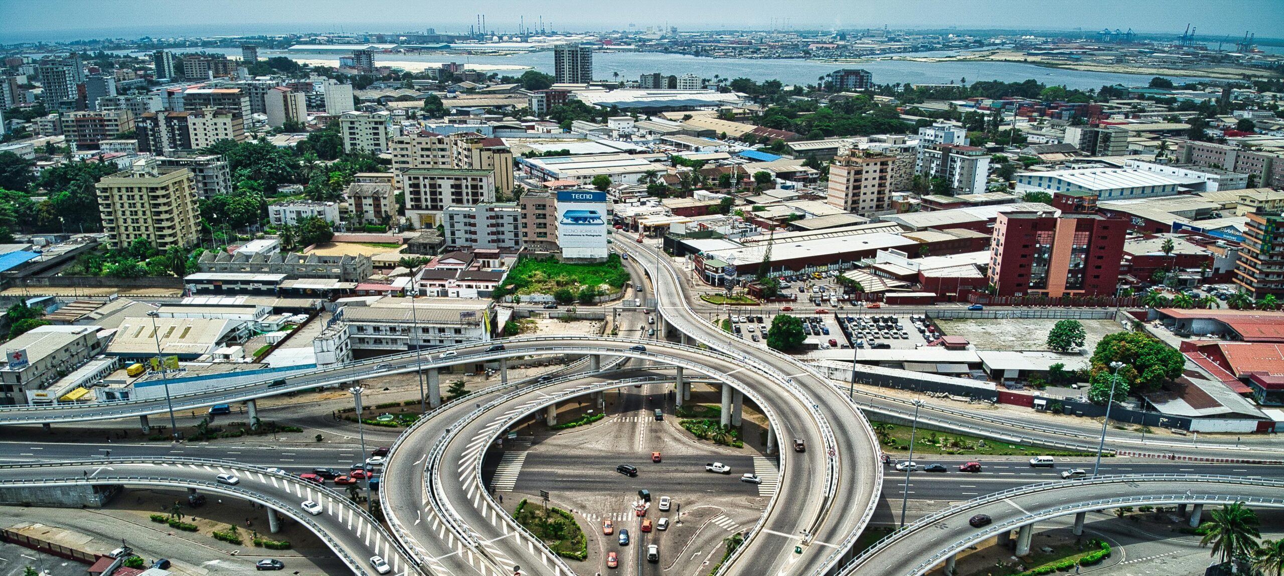 A vibrant aerial view showcasing the bustling expressways and urban landscape of Abidjan, Côte d'Ivoire.